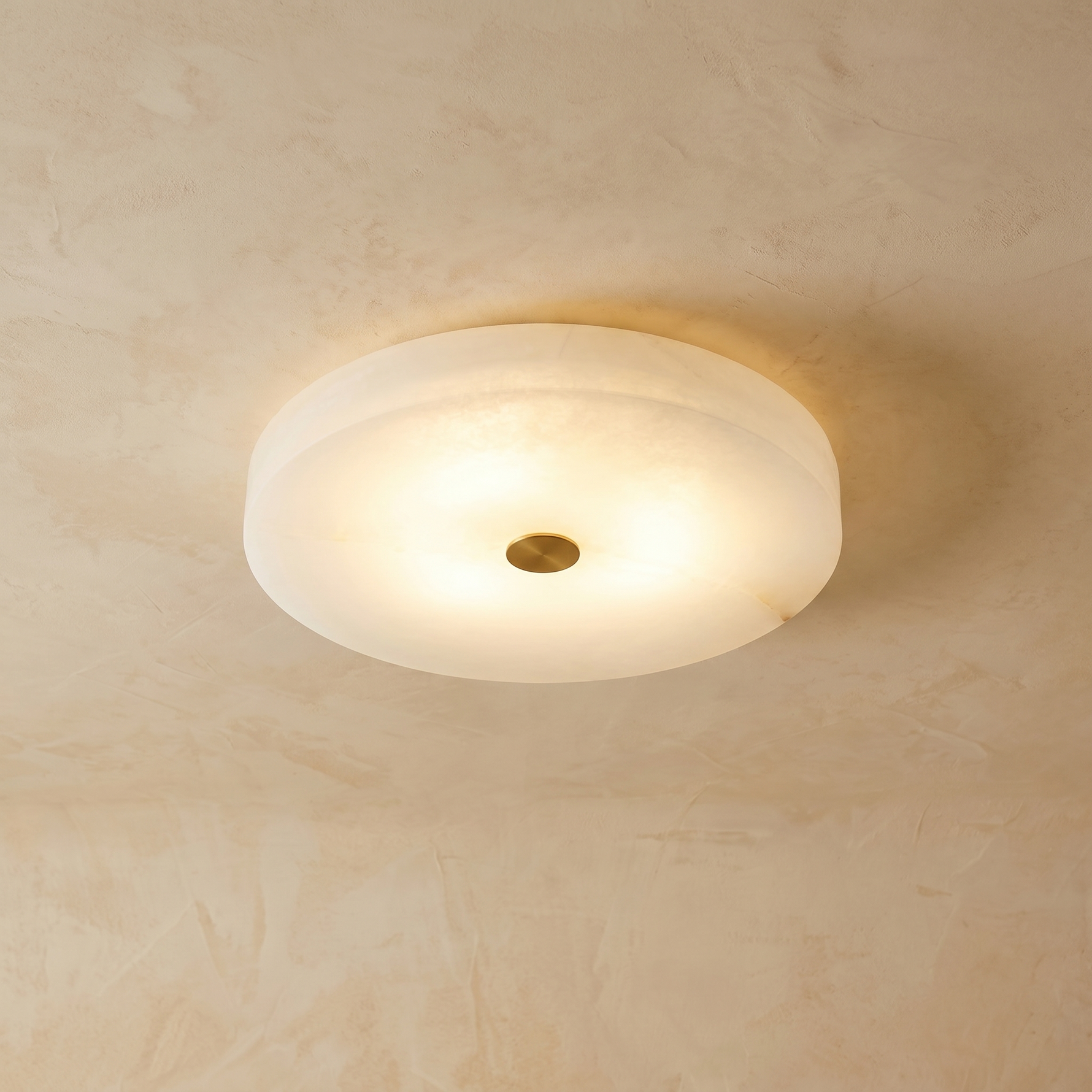 Orbita alabaster flush mount ceiling light on warm cream venetian plaster wall — modern hero shot