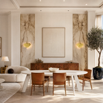A sculptural metal wall sconce shaped like a ginkgo leaf with a textured gold finish and a curved neck.