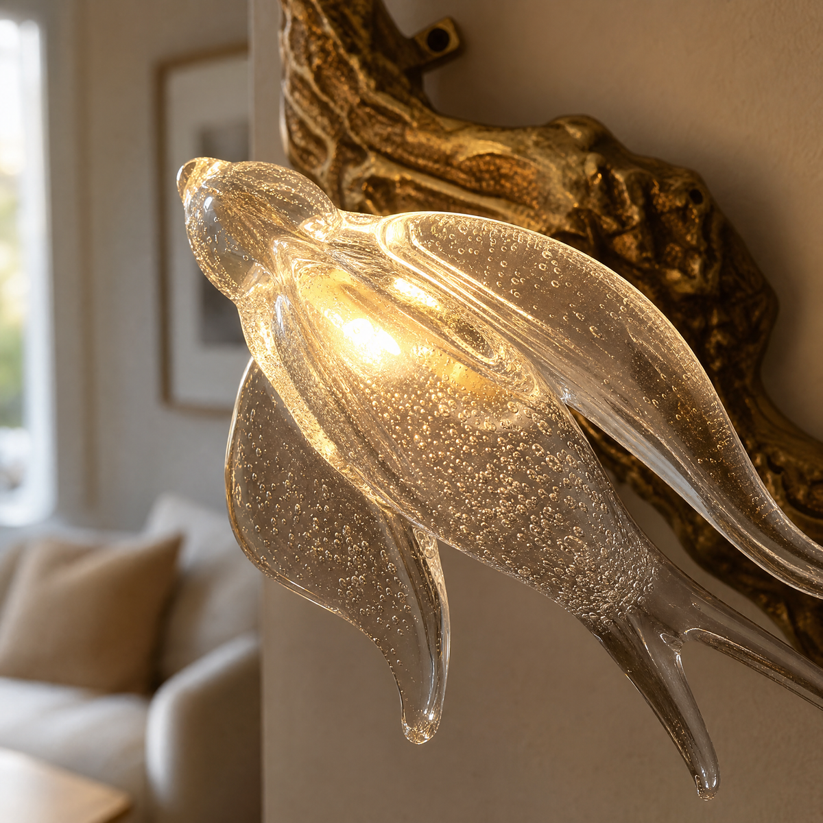 A modern wall sconce with a sculptural, branch-like frame in an antique brass finish and clear textured glass bloom shades.