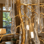 A tiered gold chandelier featuring cascading clear crystal icicle pendants suspended from a metallic branch-like frame.