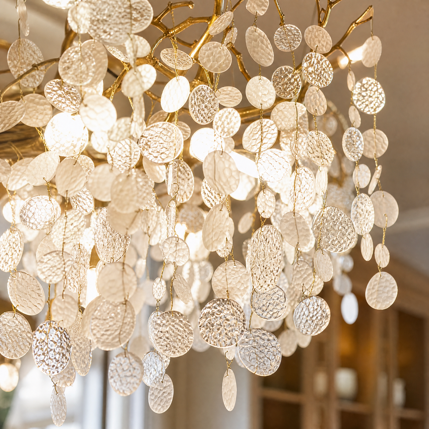 A brass branch chandelier featuring suspended frosted glass leaf elements that provide ambient light.