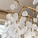 A modern organic branch chandelier with a warm gold metal frame and frosted white crystal petal accents.