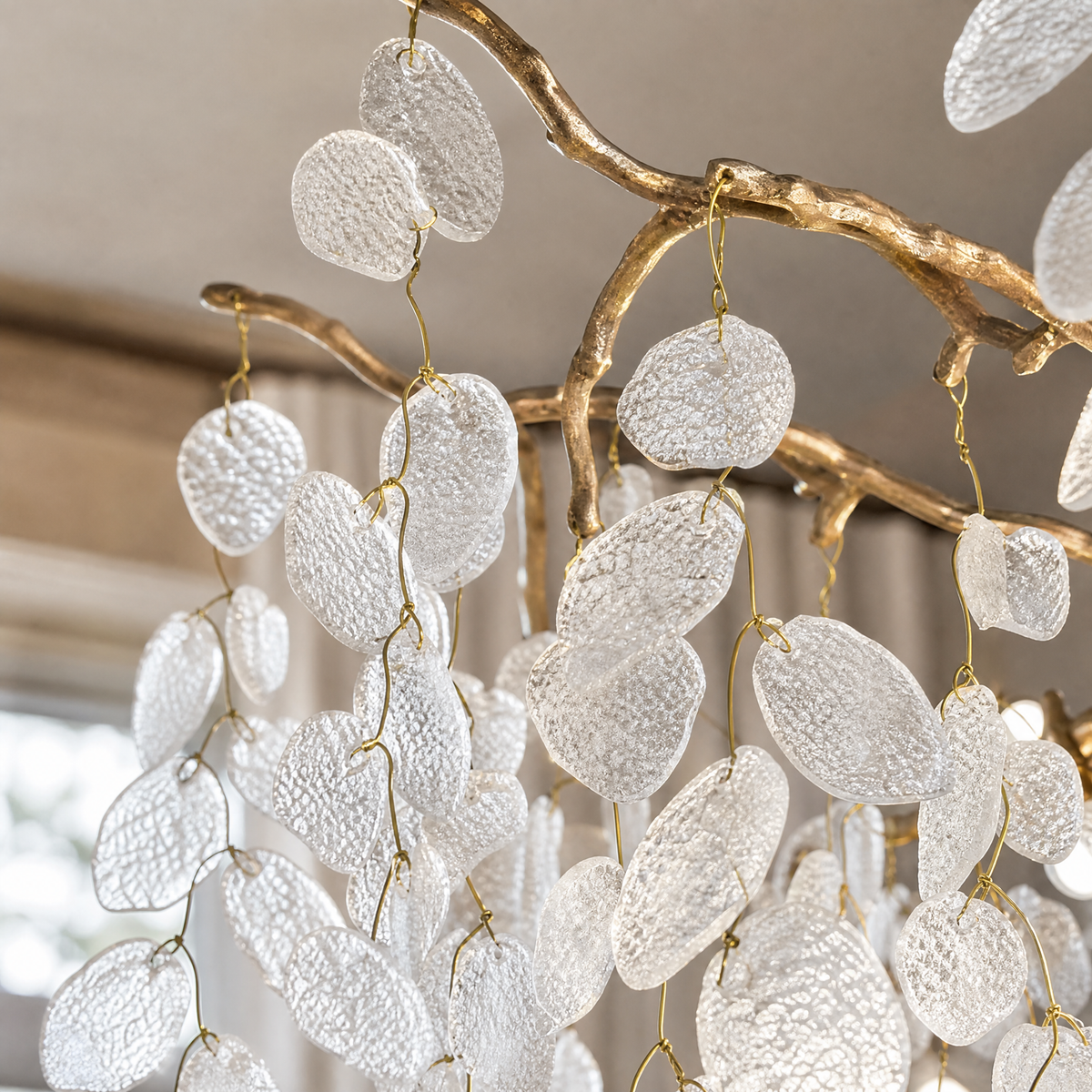 A modern organic branch chandelier with a warm gold metal frame and frosted white crystal petal accents.