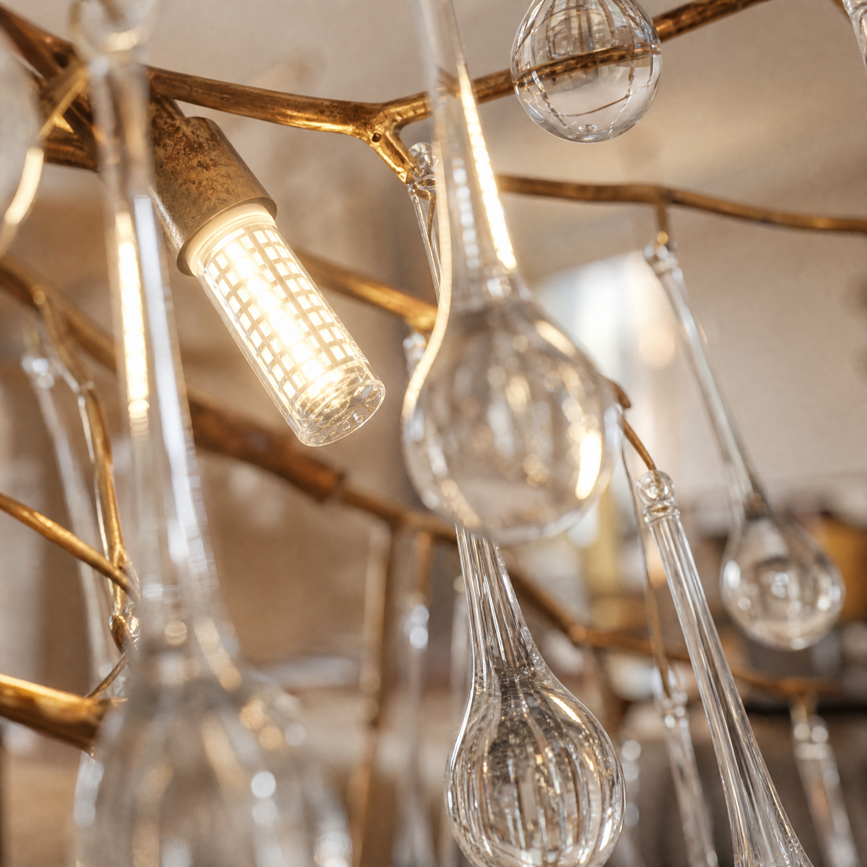 An antique brass branch chandelier adorned with hanging teardrop and icicle crystal pendants against a soft background.