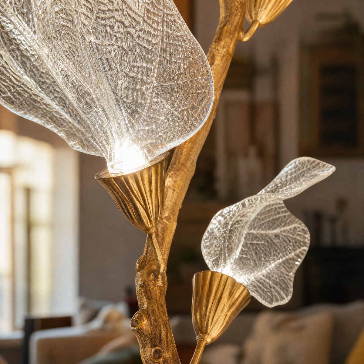A brass branch-inspired chandelier featuring cascading frosted leaf-shaped glass shades hanging vertically.