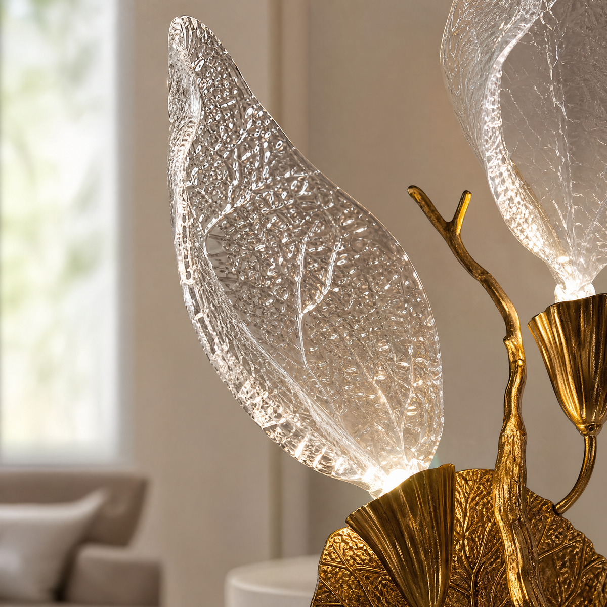 A wall sconce featuring sculpted leaf-shaped textured glass shades and a warm gold metal finish.
