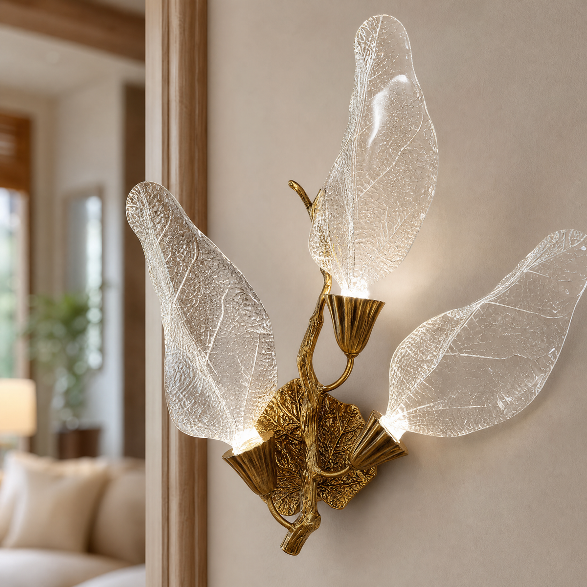 A wall sconce featuring sculpted leaf-shaped textured glass shades and a warm gold metal finish.