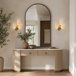 A wall sconce featuring sculpted leaf-shaped textured glass shades and a warm gold metal finish.
