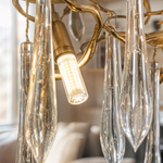A brass branch chandelier featuring cascading clear crystal raindrop prisms suspended by slim metal cables.