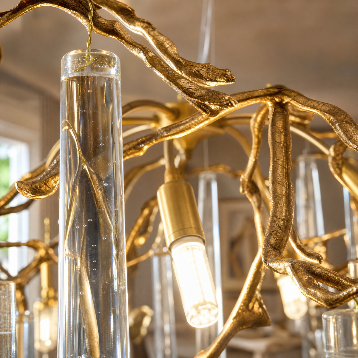 A brass branch chandelier featuring cascading clear crystal raindrop prisms suspended by slim metal cables.