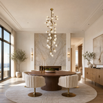A modern chandelier with an antique brass metal vine frame and glowing glass buds hanging in a bright room.