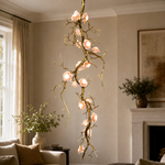 An antique brass branch chandelier with blooming floral glass shades suspended from a ceiling canopy mount.