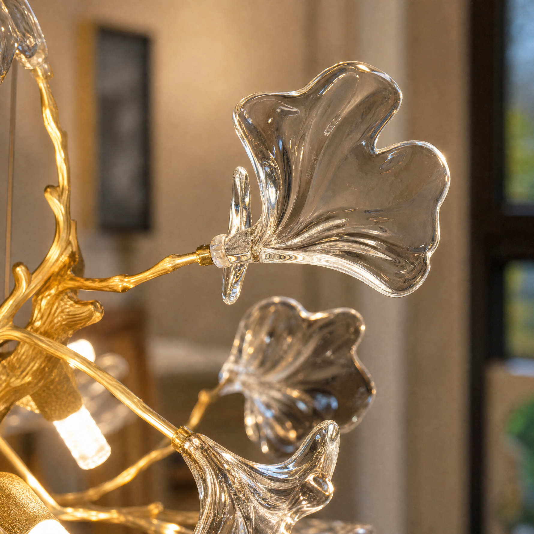 A gold metal branch chandelier with crystal ginkgo leaf shades suspended from a circular canopy.