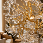 A gold metal branch chandelier with crystal ginkgo leaf shades suspended from a circular canopy.