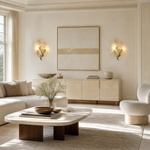 A modern wall sconce designed as a sculptural ginkgo branch in a warm brass finish with clear textured glass leaf shades.