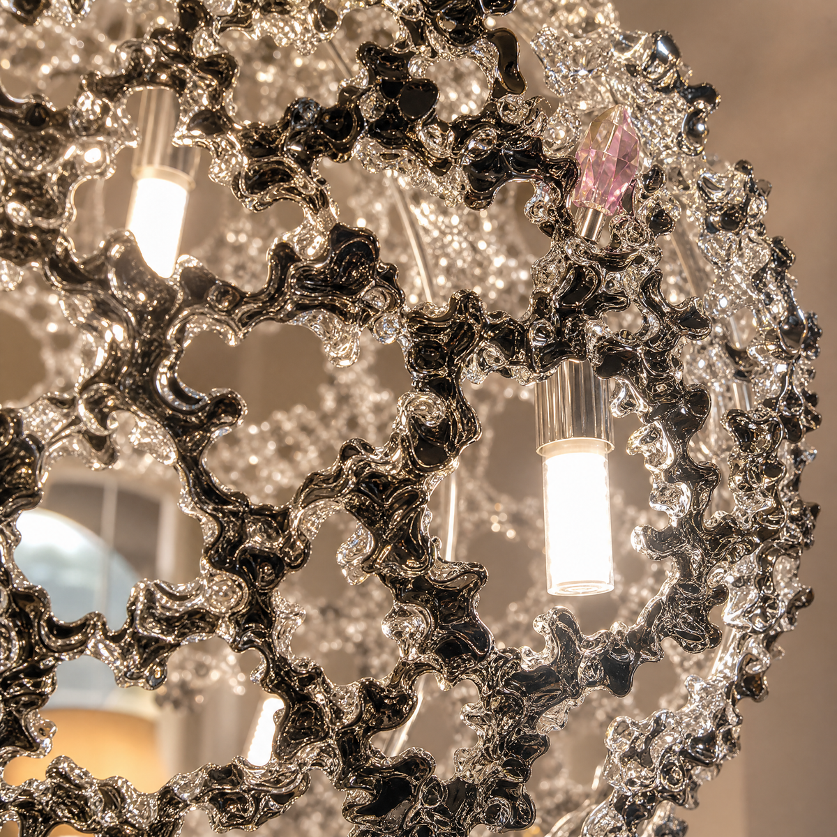 A spherical pendant light with a polished chrome lattice frame and clear crystal droplets hanging inside.