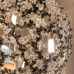 A spherical pendant light with a polished chrome lattice frame and clear crystal droplets hanging inside.