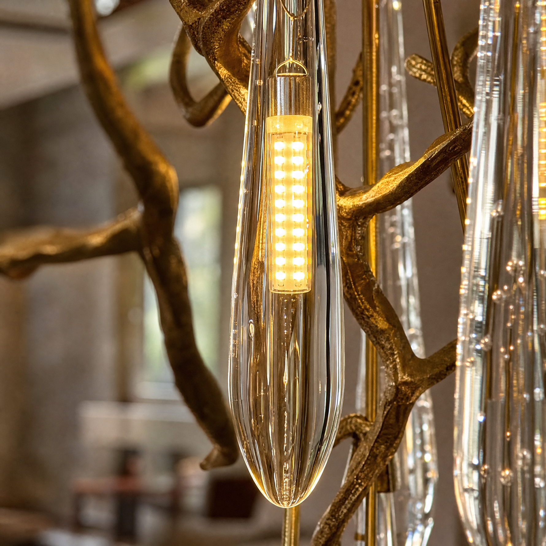 A gold metal branch frame supports a cascading waterfall of clear crystal teardrop prisms in this luxury chandelier.