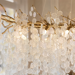 A modern branch chandelier with a gold finish features cascading textured clear glass discs, diffusing a warm ambient light.