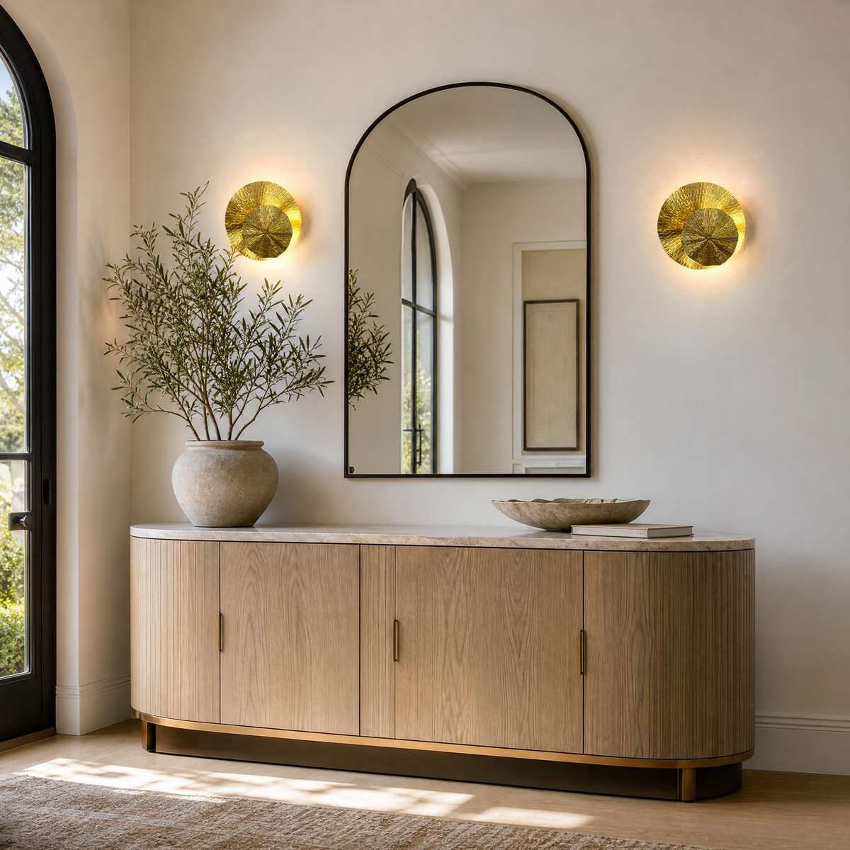 A contemporary wall sconce made of two overlapping metal discs with a textured sunburst pattern in a warm brass finish.
