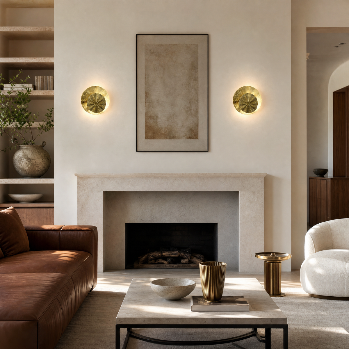 A contemporary wall sconce made of two overlapping metal discs with a textured sunburst pattern in a warm brass finish.