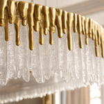 A double-tier chandelier with icicle-style textured crystal drops and a satin warm gold metal band.