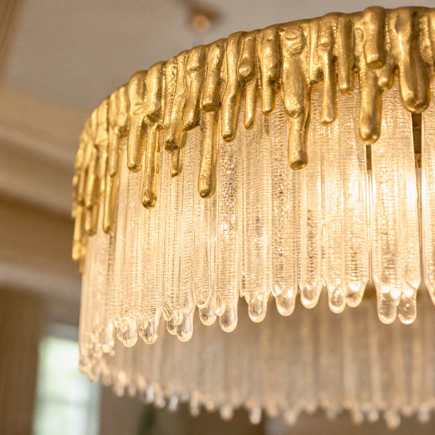 A double-tier chandelier with icicle-style textured crystal drops and a satin warm gold metal band.