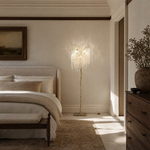 A gold metal tree floor lamp with cascading clear crystal drops standing on a square brass base.