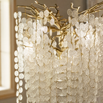 A gold metal tree floor lamp with cascading clear crystal drops standing on a square brass base.