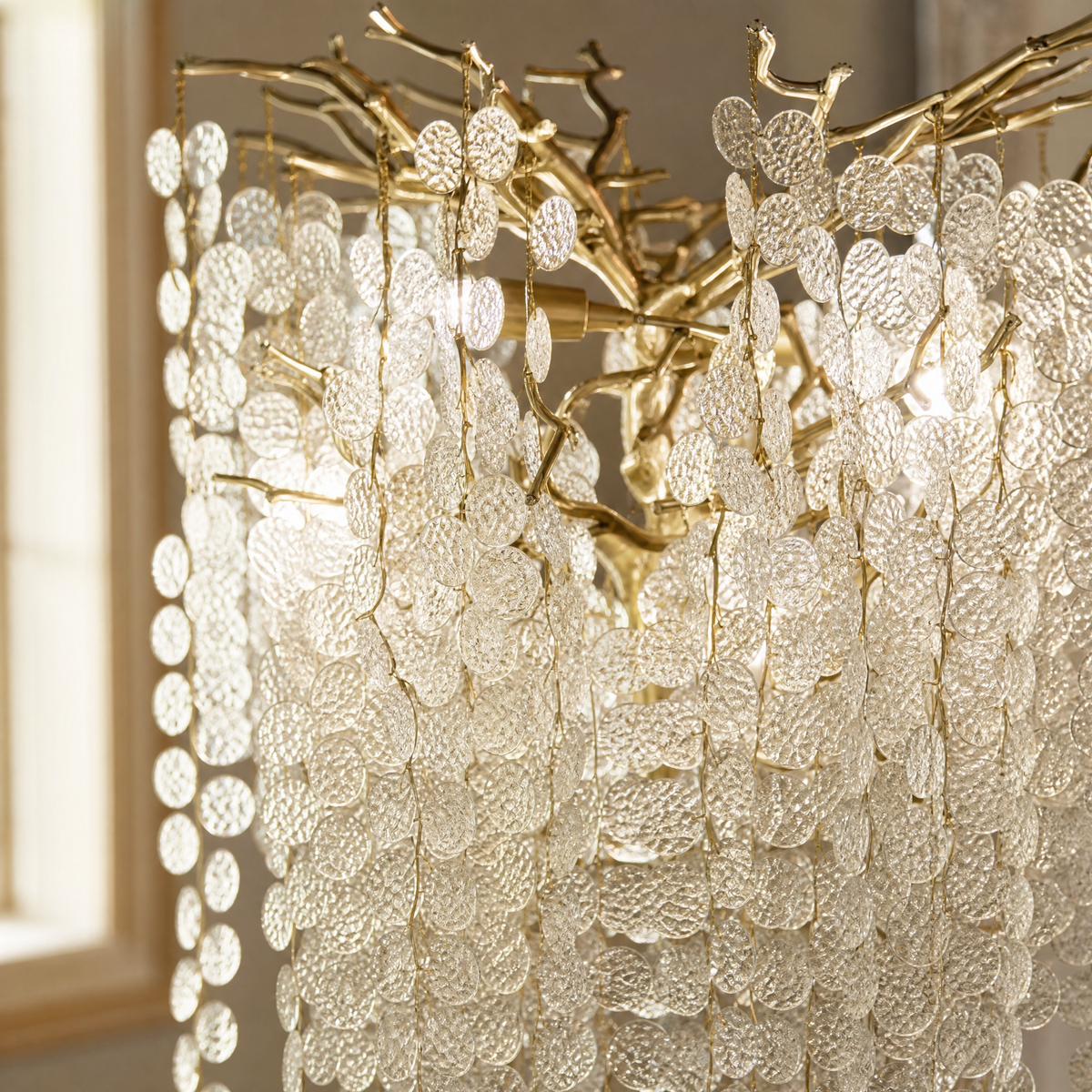 A gold metal tree floor lamp with cascading clear crystal drops standing on a square brass base.