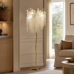 A gold metal tree floor lamp with cascading clear crystal drops standing on a square brass base.