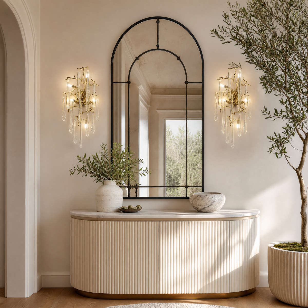 A wall sconce featuring an antique brass branch-inspired metal frame with hanging clear crystal icicle drops.