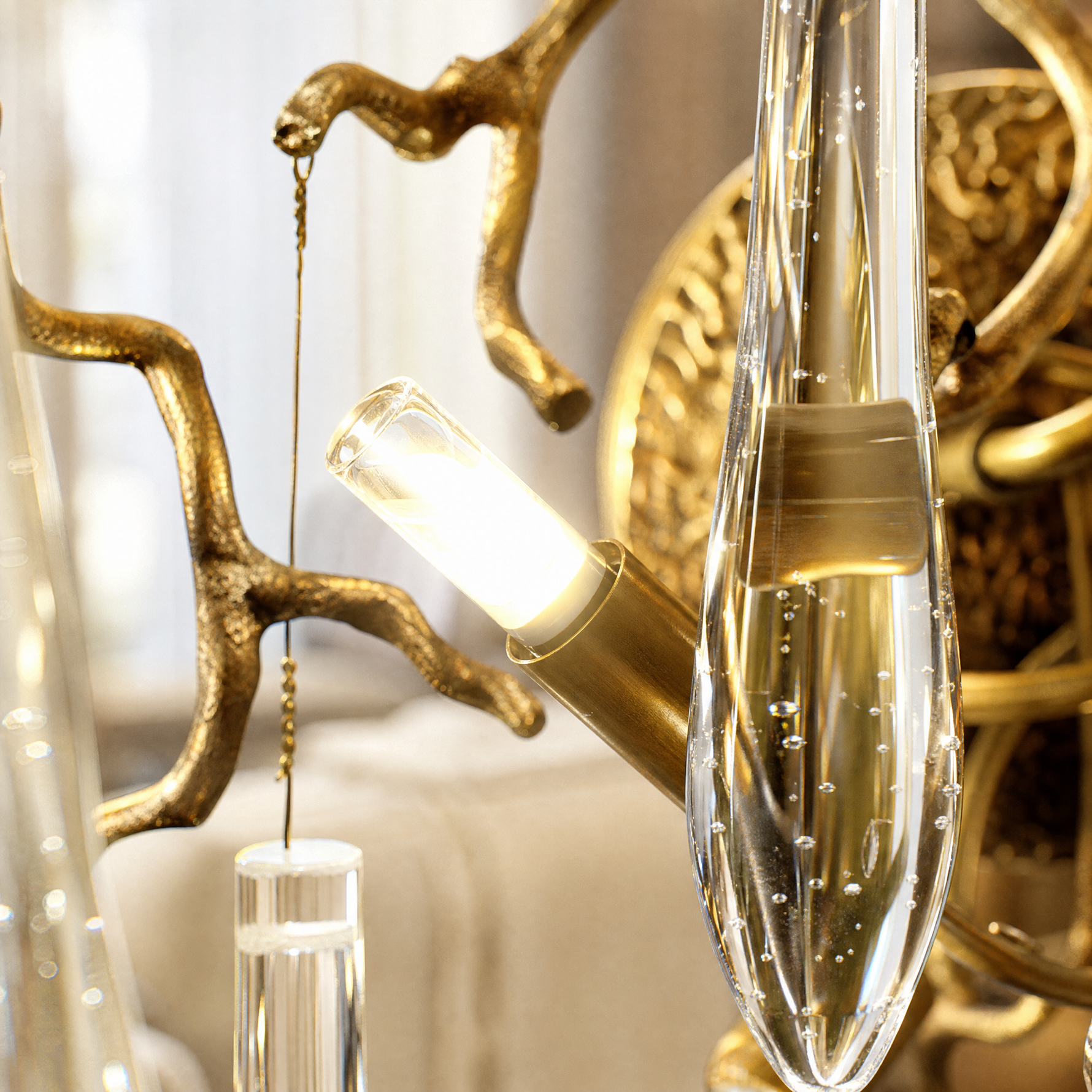 A wall sconce featuring an antique brass branch-inspired metal frame with hanging clear crystal icicle drops.