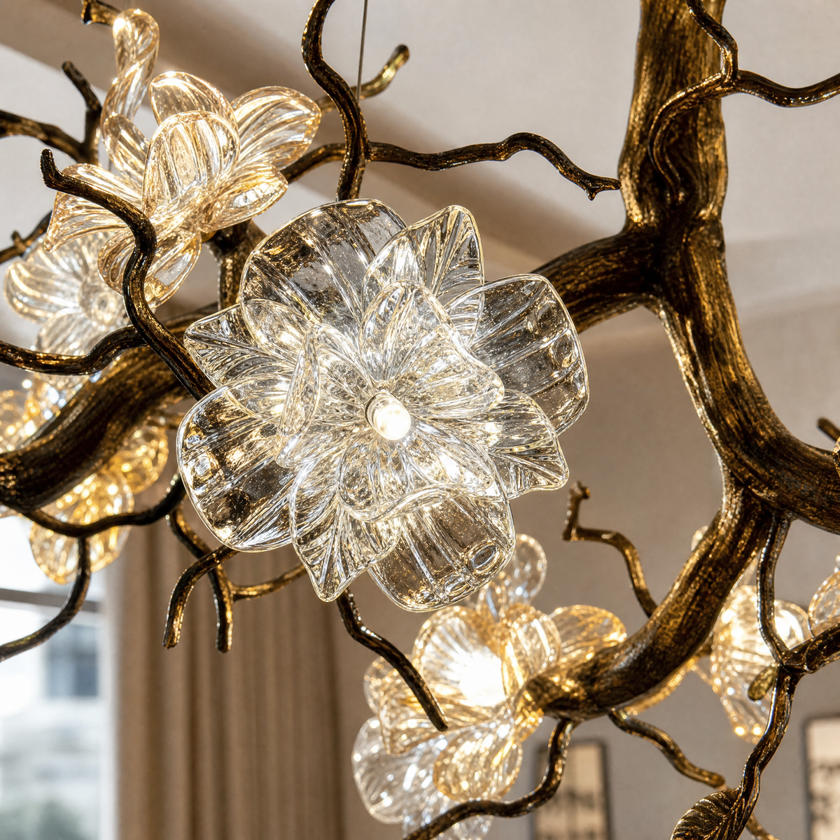An antique brass chandelier with branching arms and frosted glass blossom shades suspended by cables.