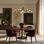 An antique brass chandelier with branching arms and frosted glass blossom shades suspended by cables.