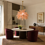 A blush pink feather pendant chandelier with a gold metal stem and circular tiered frame hangs in a bright interior space.