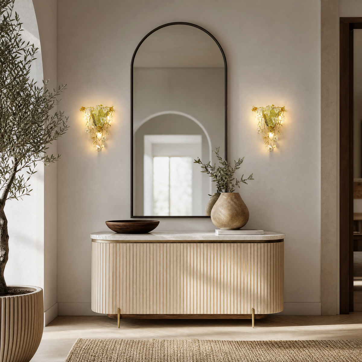 A gold metal wall sconce features a floral vine design with amber glass accents mounted on a wall.