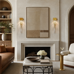 A contemporary wall sconce with a sculptural gilded gold branch frame and a single vertical crystal drop on a rectangular