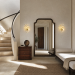 A wall sconce featuring white ceramic ginkgo leaf shades attached to a polished brass metal frame.