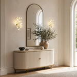 A wall sconce featuring white ceramic ginkgo leaf shades attached to a polished brass metal frame.