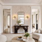 A wall sconce featuring a gold branch-shaped metal frame decorated with hanging teardrop crystal accents.