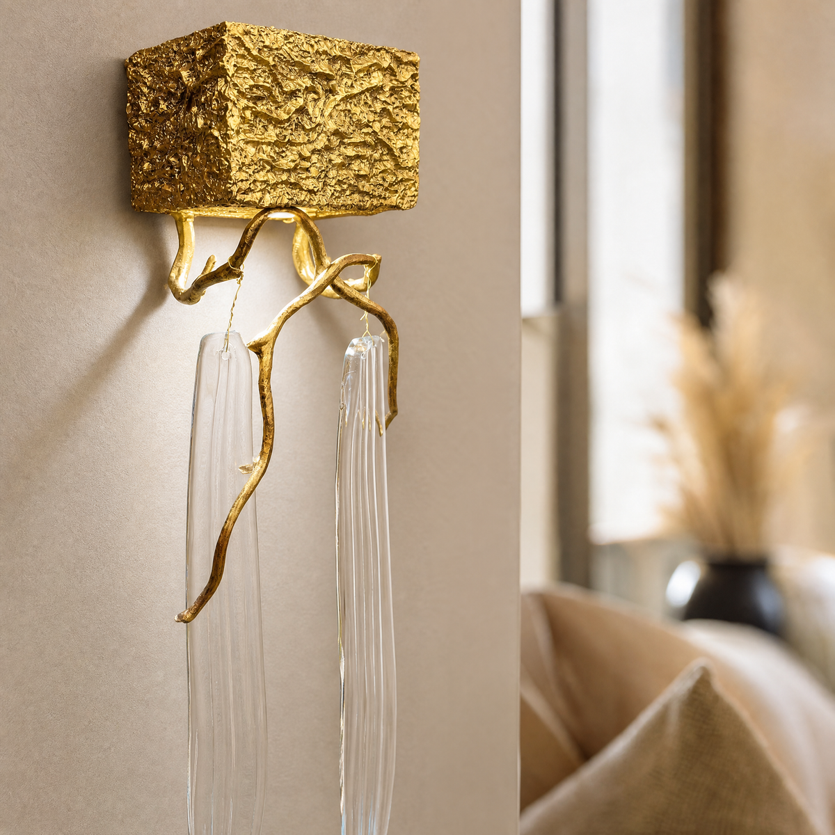 A textured gold metal wall sconce with organic branch accents and elongated fluted clear crystal pendants.