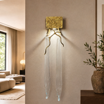 A textured gold metal wall sconce with organic branch accents and elongated fluted clear crystal pendants.