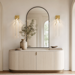 A textured gold metal wall sconce with organic branch accents and elongated fluted clear crystal pendants.