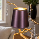 A decorative table lamp with a textured gold branch frame, hanging clear crystal droplets, and dual teal and purple shades.