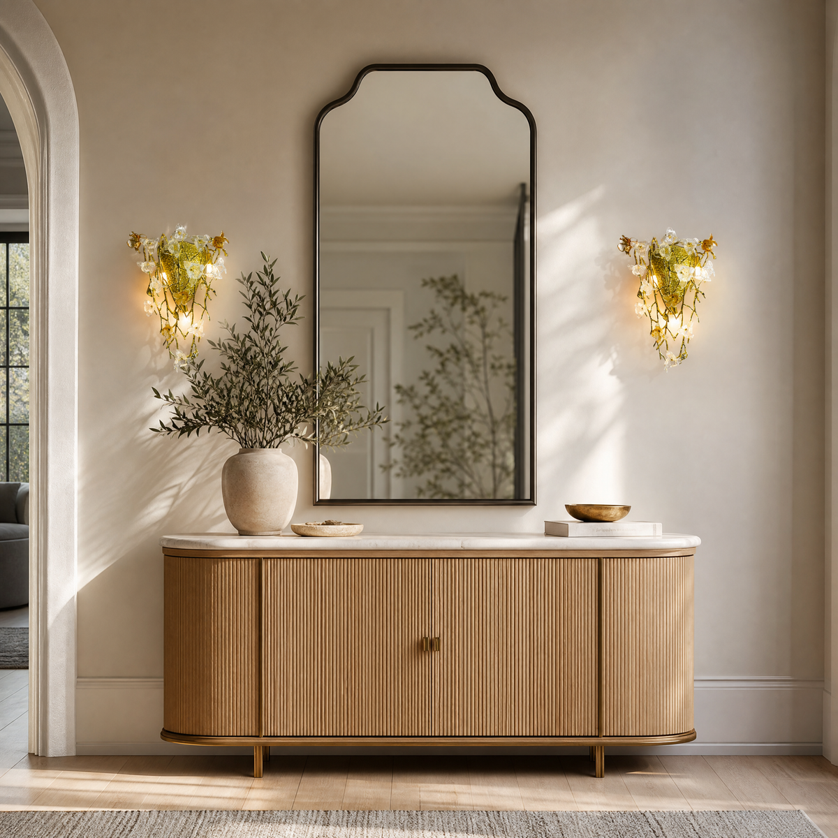 A gold metal wall sconce with a sculptural orchid floral motif and clear frosted glass accents in a triangular silhouette.