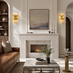 A gold metal wall sconce with a sculptural orchid floral motif and clear frosted glass accents in a triangular silhouette.