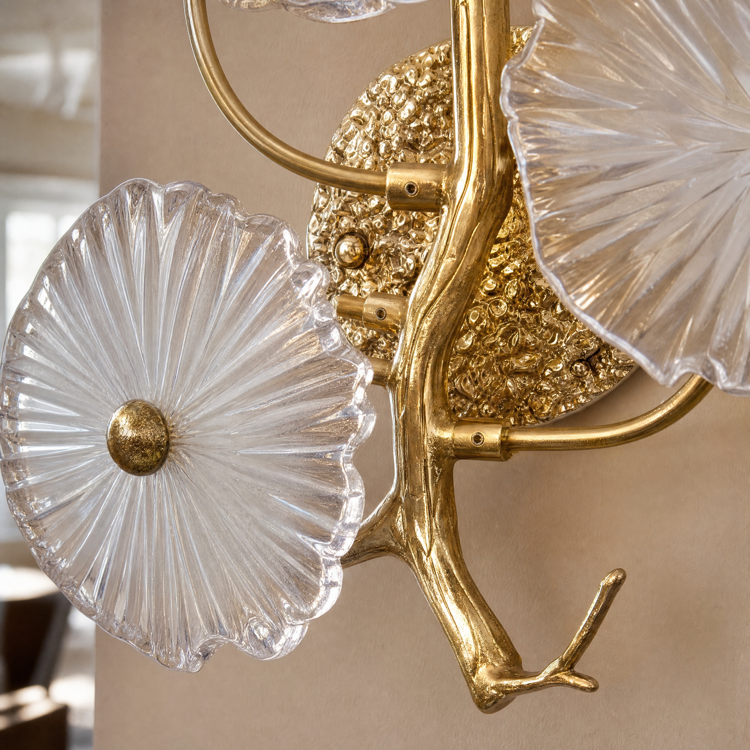A contemporary wall sconce with three frosted glass discs clustered on a sculptural, branching arm with a warm brass finish.