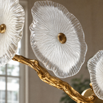 A modern wall sconce featuring an antique brass branch-like metal frame adorned with textured circular glass blossom shades.