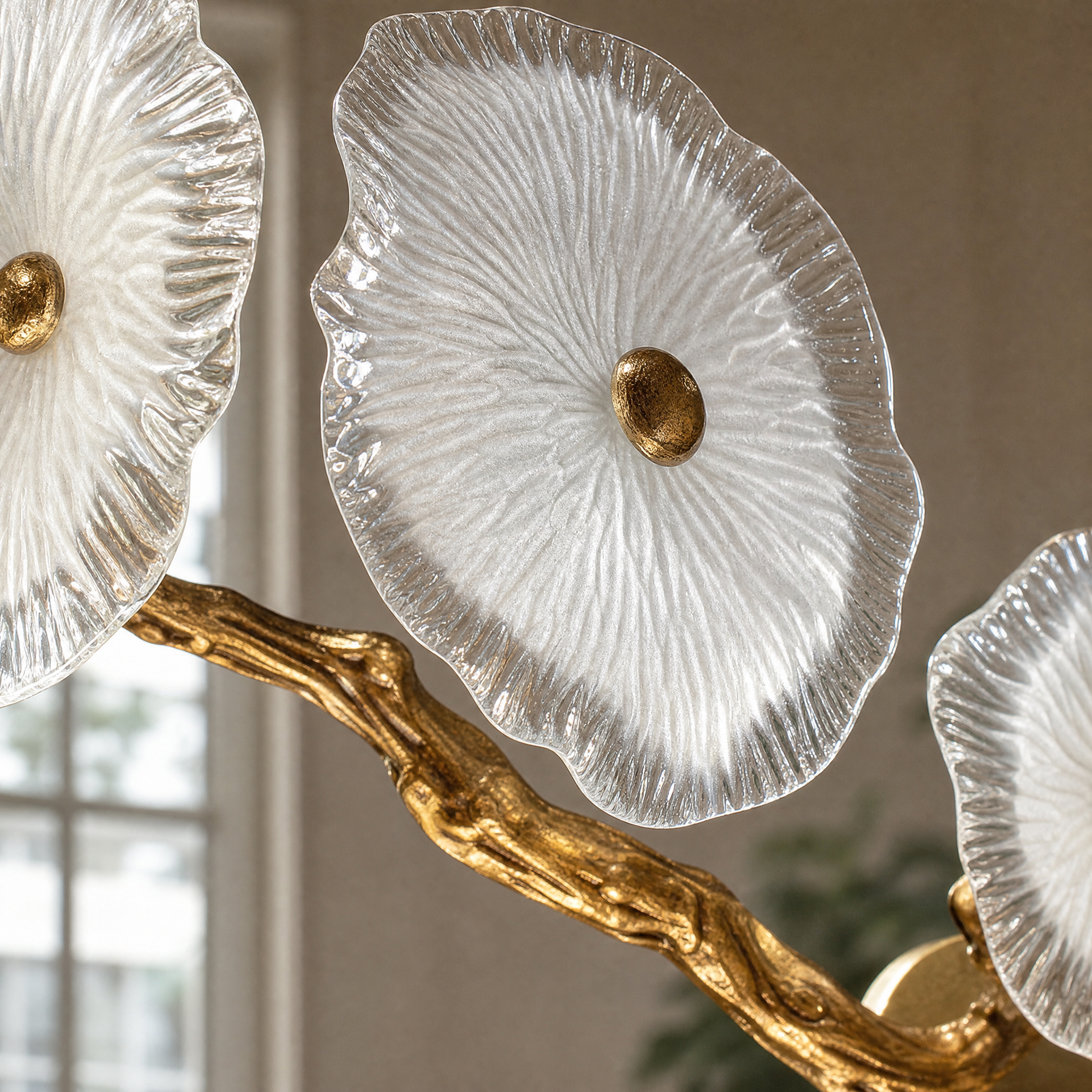 A modern wall sconce featuring an antique brass branch-like metal frame adorned with textured circular glass blossom shades.